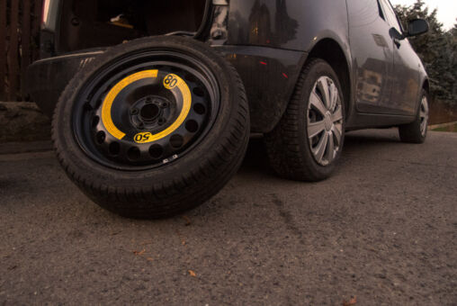The spare tire leaning against a black car
