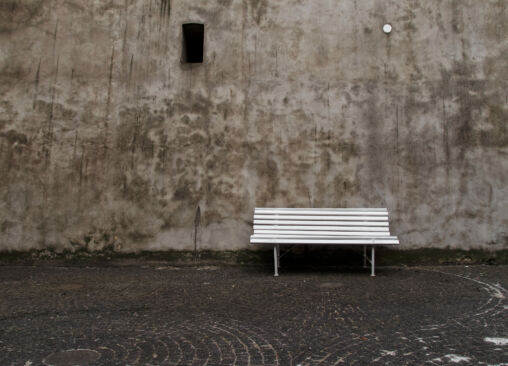 Empty white bench in front of the old wall