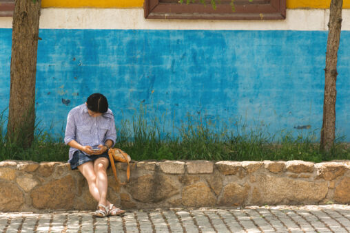 Young woman sitting with phone on the street